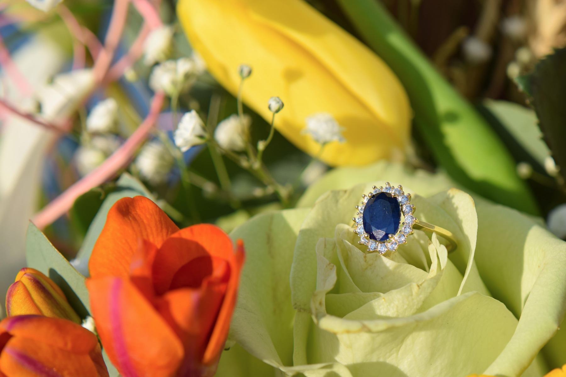 Златен пръстен със сапфир върху цветя